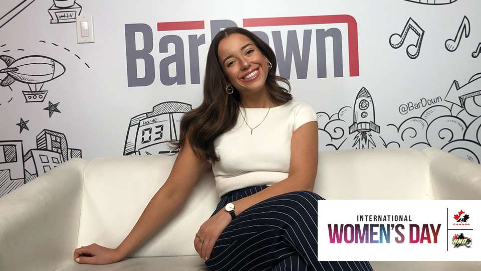 A woman sitting on a white couch with the words barrow international women's day, empowering others to ALWAYS BE YOURSELF.